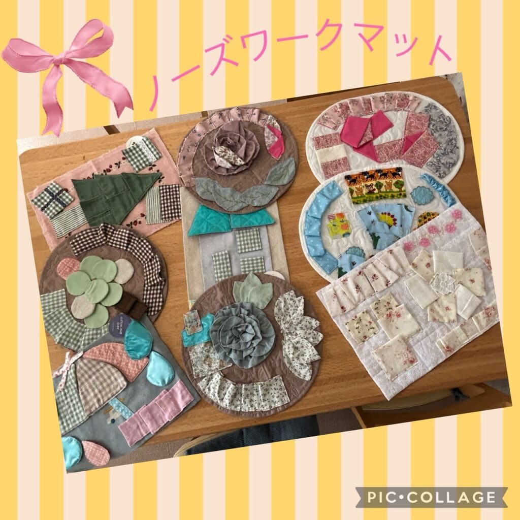 布帛素材で作られたノーズワークマットがテーブルに並んでいる様子。花や木などの形に布を縫い合わせた手作り作品。