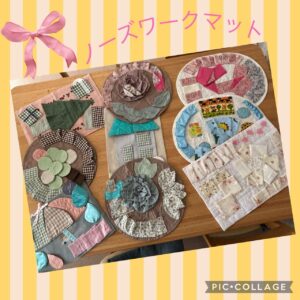 布帛素材で作られたノーズワークマットがテーブルに並んでいる様子。花や木などの形に布を縫い合わせた手作り作品。