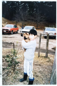 幼い男の子が、子犬を大切に抱きしめている屋外での写真