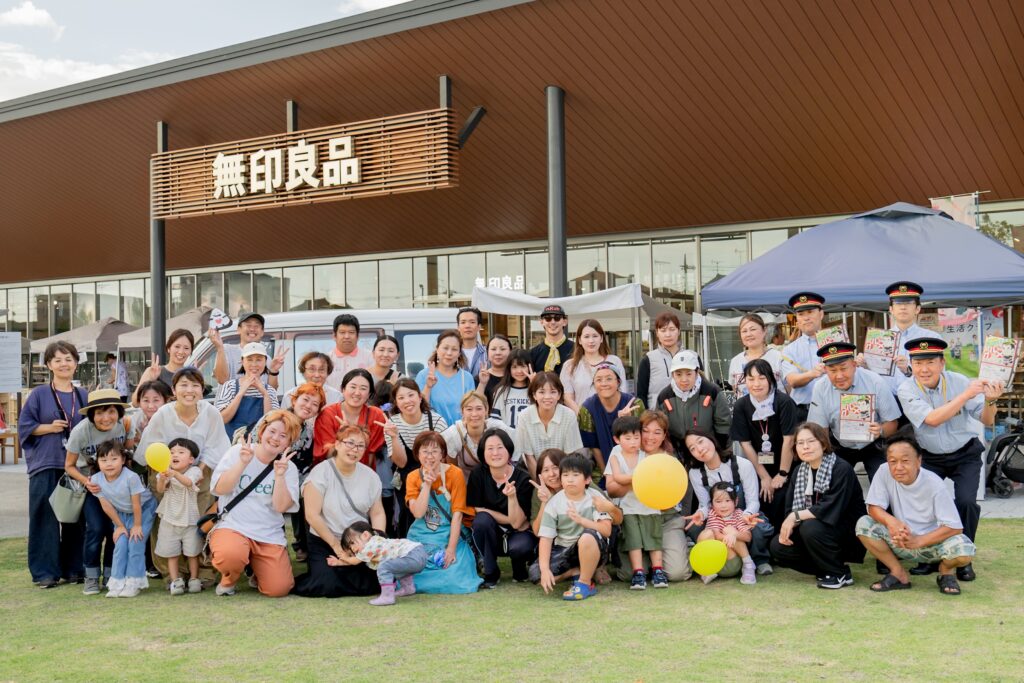 無印良品 東武動物公園駅前店前で撮影された、出店者・関係者による集合写真。約40名が笑顔でカメラに向かってポーズ。