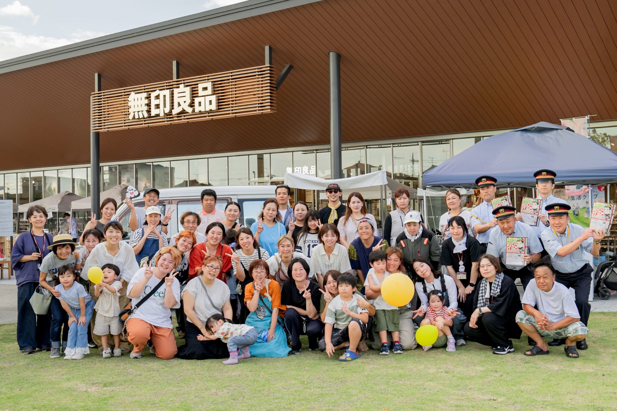 無印良品 東武動物公園駅前店前で撮影された、出店者・関係者による集合写真。約40名が笑顔でカメラに向かってポーズ。