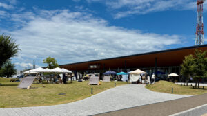夏空の下で開催された「むじるしのなつぞらひろば」の外観風景。無印良品店舗前に多数のテントが並び、マルシェが広がる。
