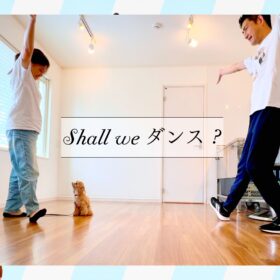 室内で犬と飼い主2人が向かい合い、腕を広げてポーズを取るドッグダンスレッスンの様子