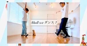 室内で犬と飼い主2人が向かい合い、腕を広げてポーズを取るドッグダンスレッスンの様子