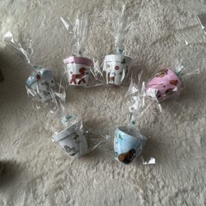 犬のイラストが描かれたデコパージュ鉢が6つ並び、透明のラッピングで包まれている様子。