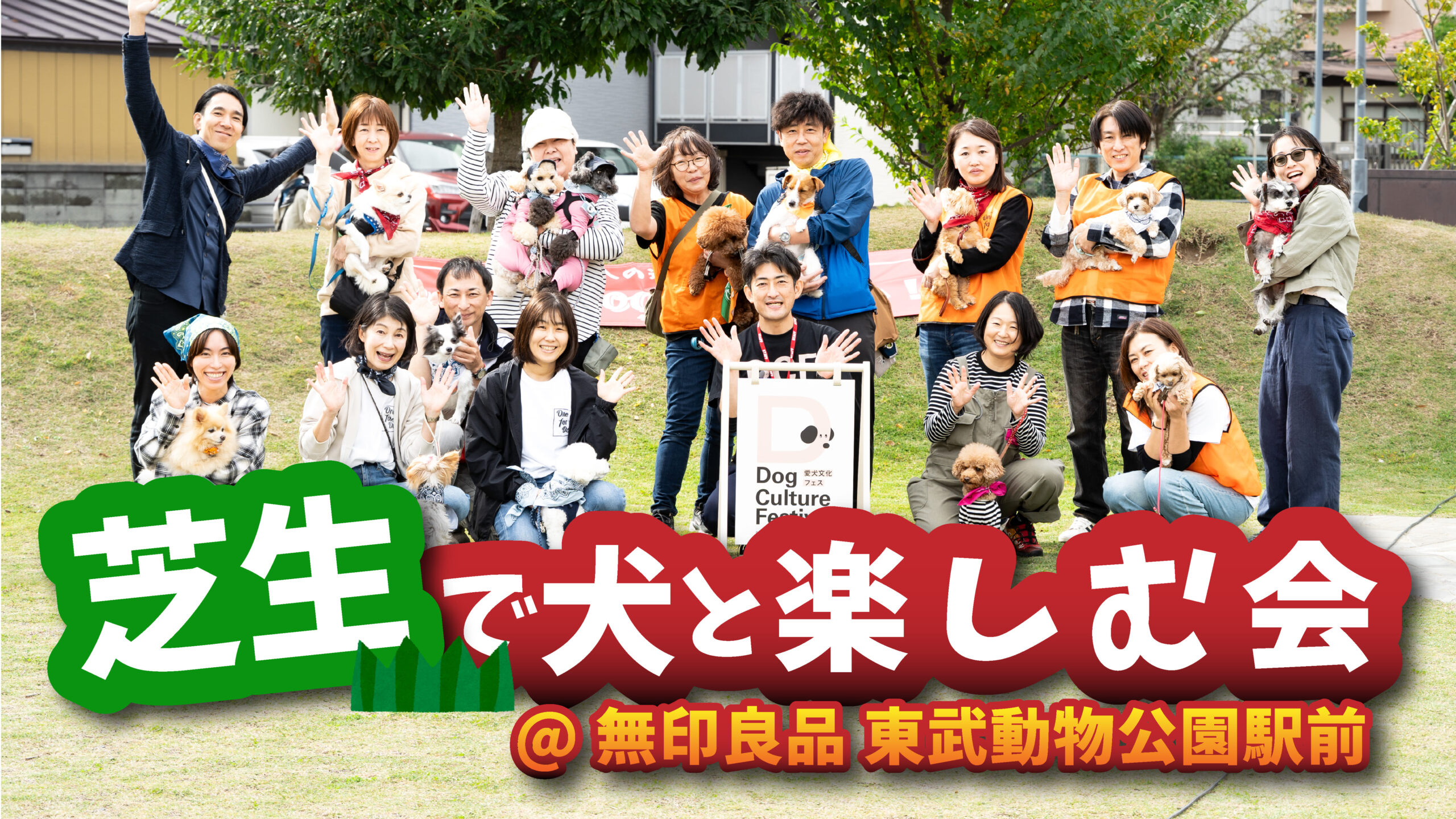 芝生の広場で、愛犬と一緒にポーズをとる参加者たちの集合写真。背景には木々と施設があり、前面には『芝生で犬と楽しむ会＠無印良品 東武動物公園駅前』の大きなタイトルロゴが配置されている。