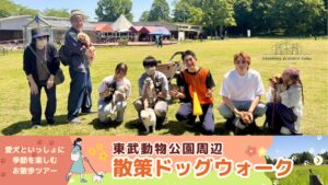東武動物公園周辺で開催された「散策ドッグウォーク」の集合写真。愛犬家のご家族とスタッフが芝生広場に集まり、和やかな雰囲気で記念撮影をしている様子。