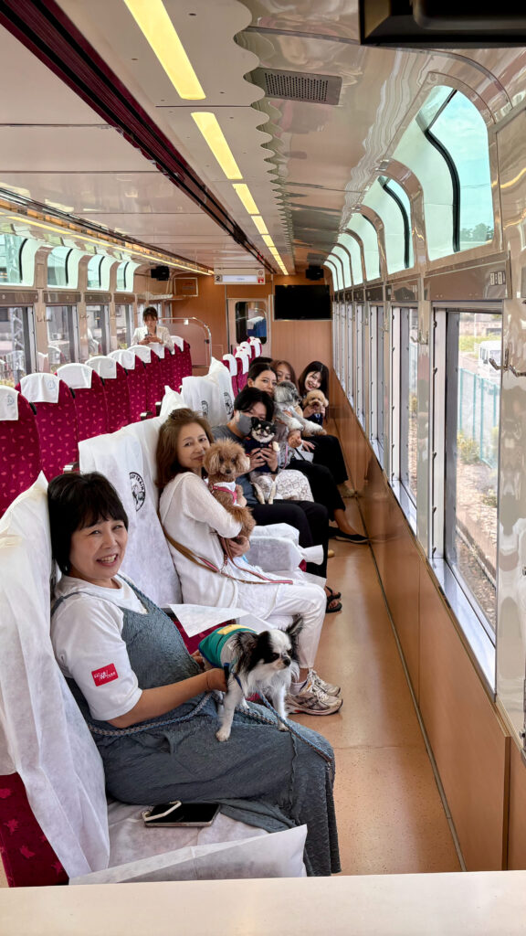 貸切列車の車内で、愛犬を抱きながら笑顔を見せるTOBU Doggy Doggy Trainの参加者たち